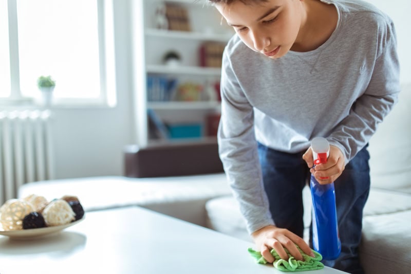 boy cleaning coffee table at home.